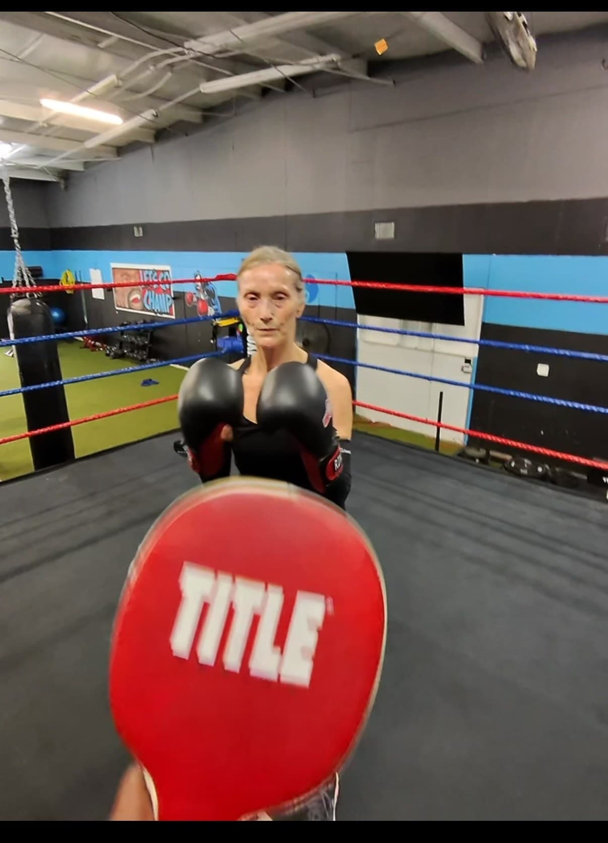 Coach holding a focus mitt for a senior member inside the ring
